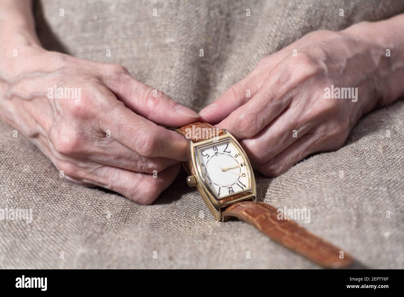 Die Hände der alten Frau halten eine Armbanduhr aus nächster Nähe. Teil des Körpers. Stockfoto