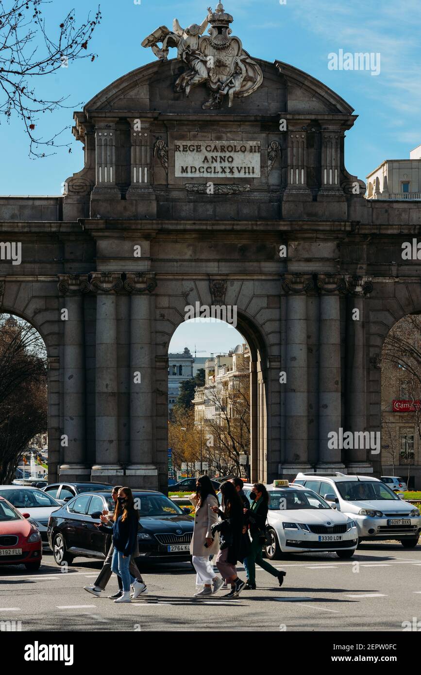 Madrid, Spanien - 28. Februar 2021: Fußgänger mit Gesichtsmaske überqueren vor dem berühmten Alcala-Tor am Unabhängigkeitsplatz, Madrid Stockfoto