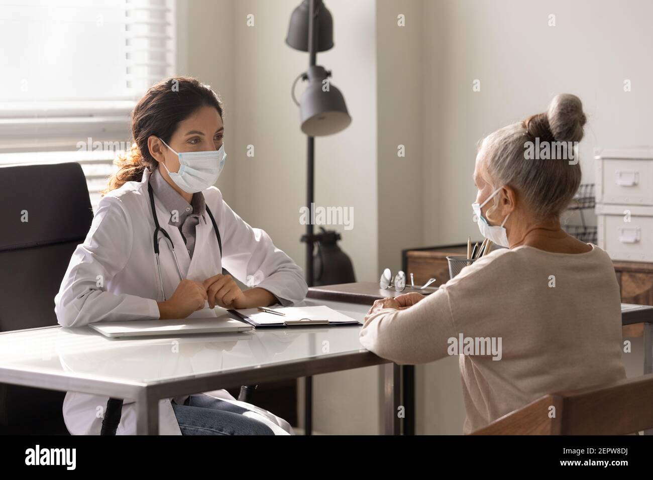 Arzt trägt Gesichtsmaske Beratung reife Frau bei der Sitzung Stockfoto