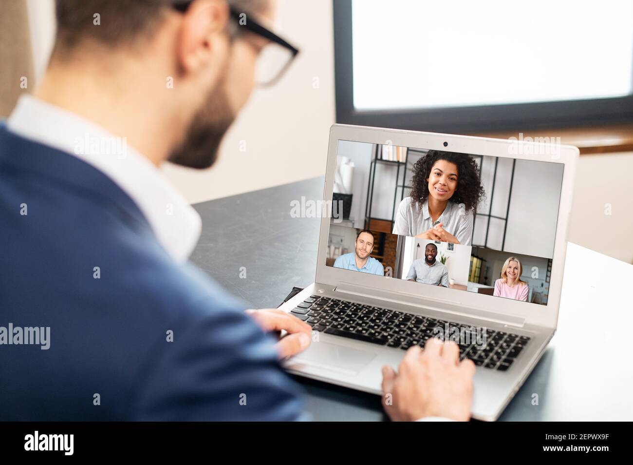 Bärtiger Geschäftsmann in Brille und formeller Kleidung mit App für die Fernkommunikation mit Kollegen, Networking, Treffen online in Pandemie, Blick auf den Laptop-Bildschirm mit Menschen-Profile Stockfoto