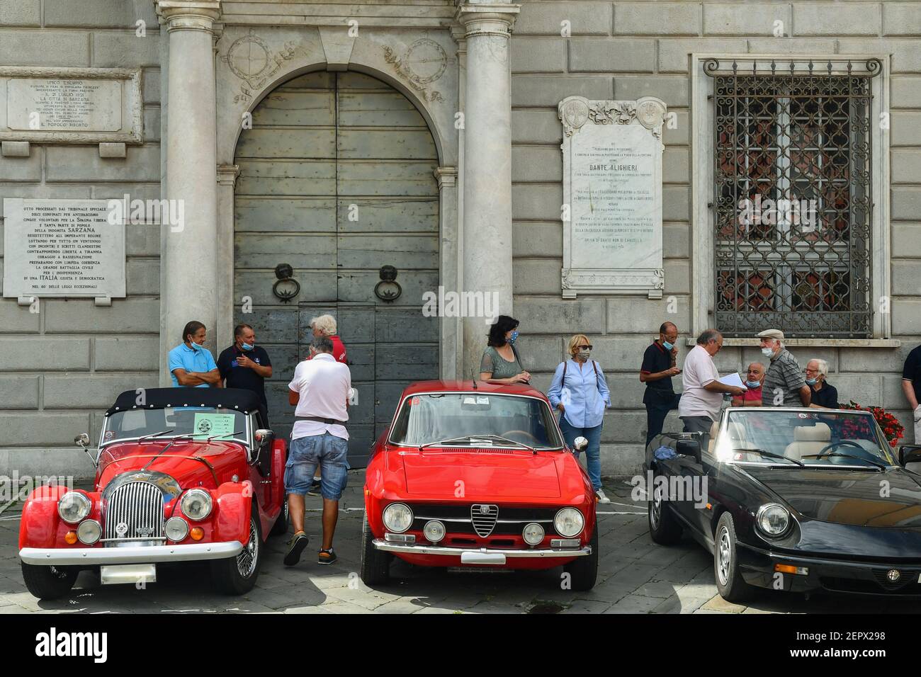 Oldtimer-Rallye mit Alfa Romeo und Morgan Autos geparkt vor dem Rathaus von Sarzana mit Menschen im Sommer, La Spezia, Ligurien, Italien Stockfoto