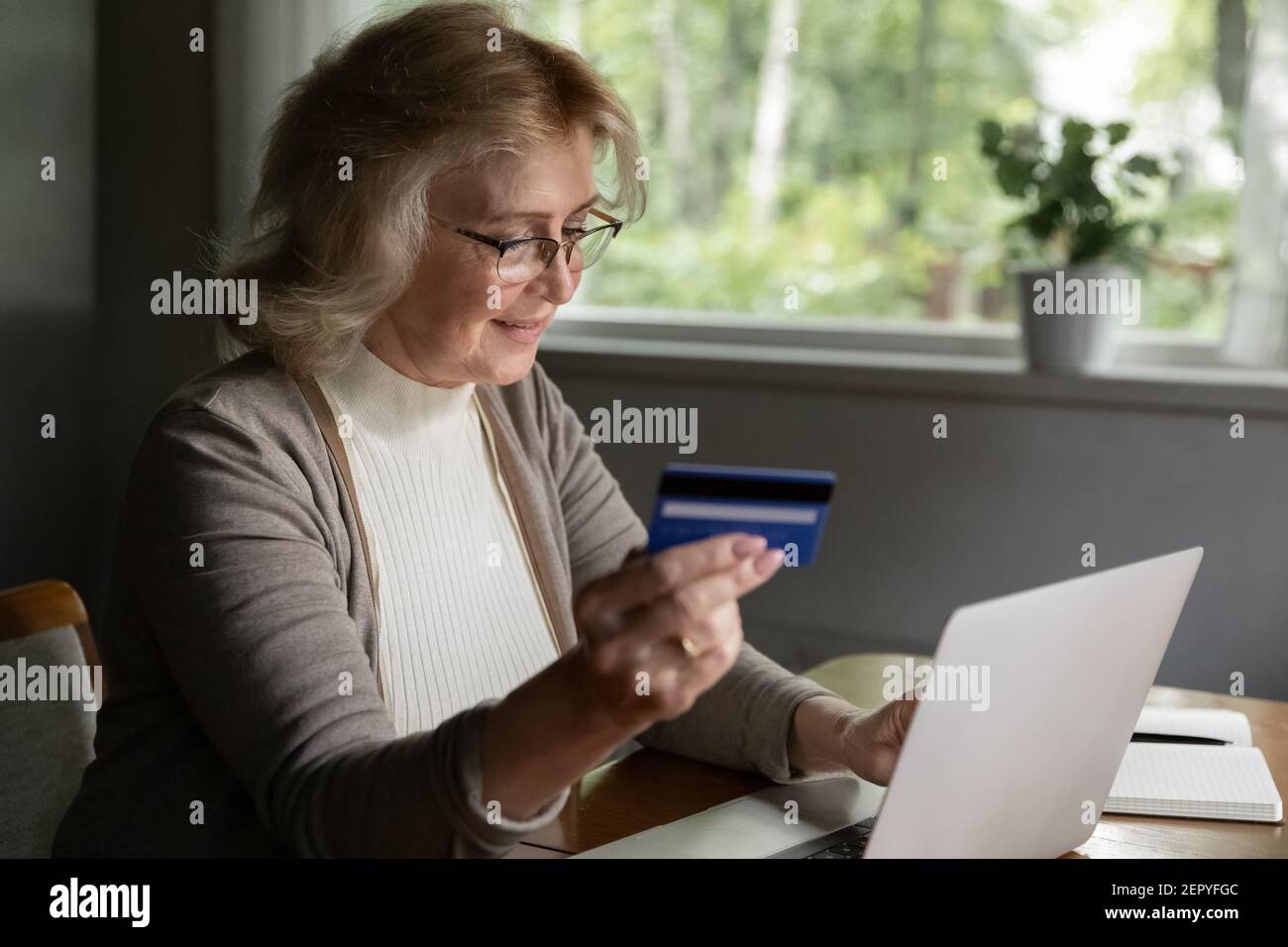 Ein glücklicher, mittelalter Kunde im Alter von 50s Jahren mit Kreditkarte Stockfoto