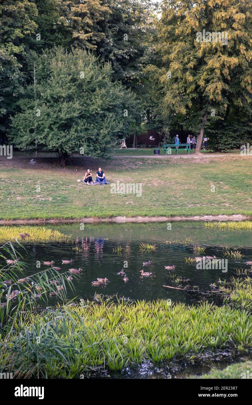 Lviv, Ukraine - 28. August 2020: Menschen, die in der Nähe von See in der Stadt öffentlichen Park ruhen Stockfoto