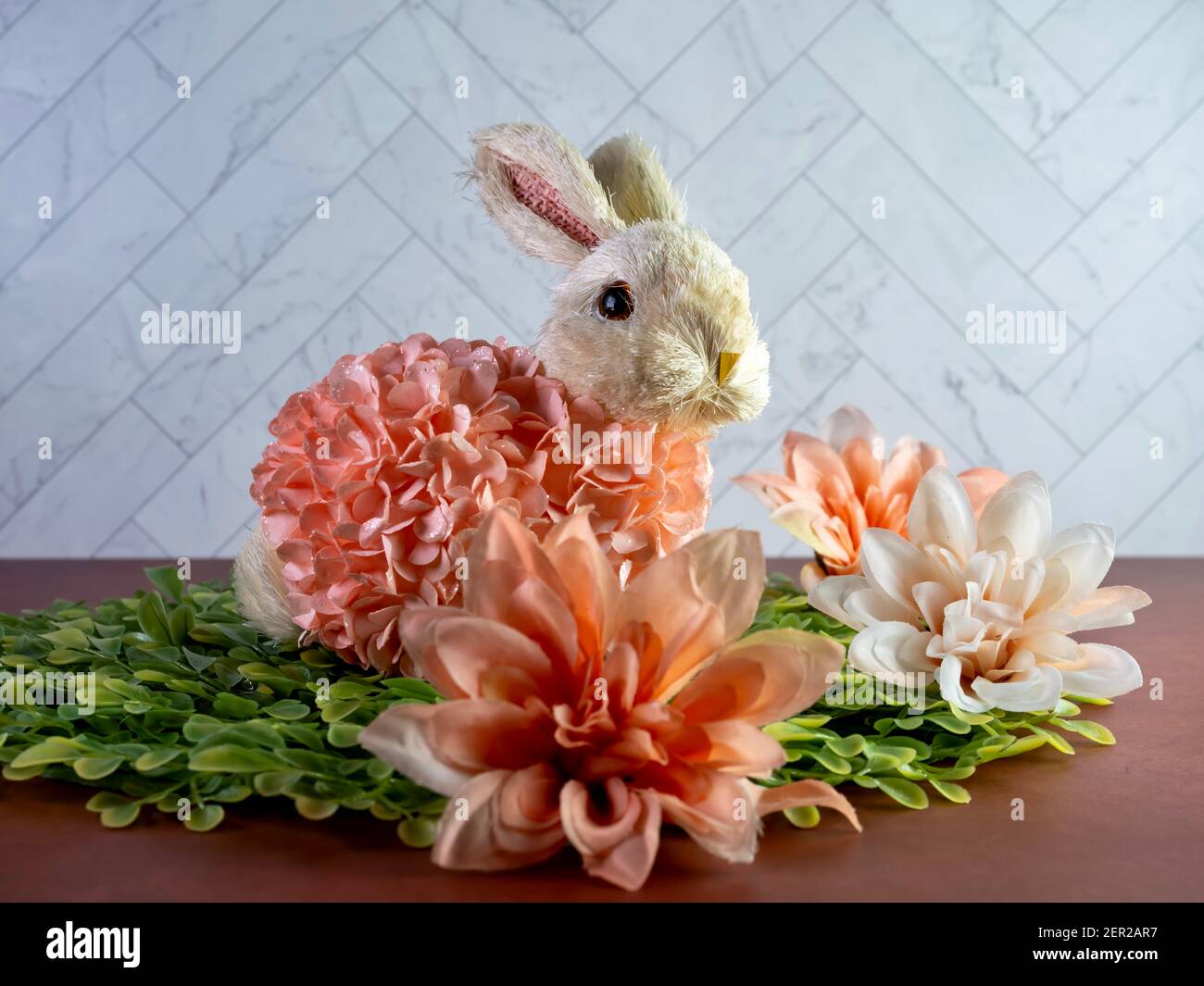 Osterhase Dekor sitzt auf grünen Blättern von Pfirsich künstliche Dahlia Blume Blüten umgeben, perfekt für den Frühlingsurlaub! Stockfoto