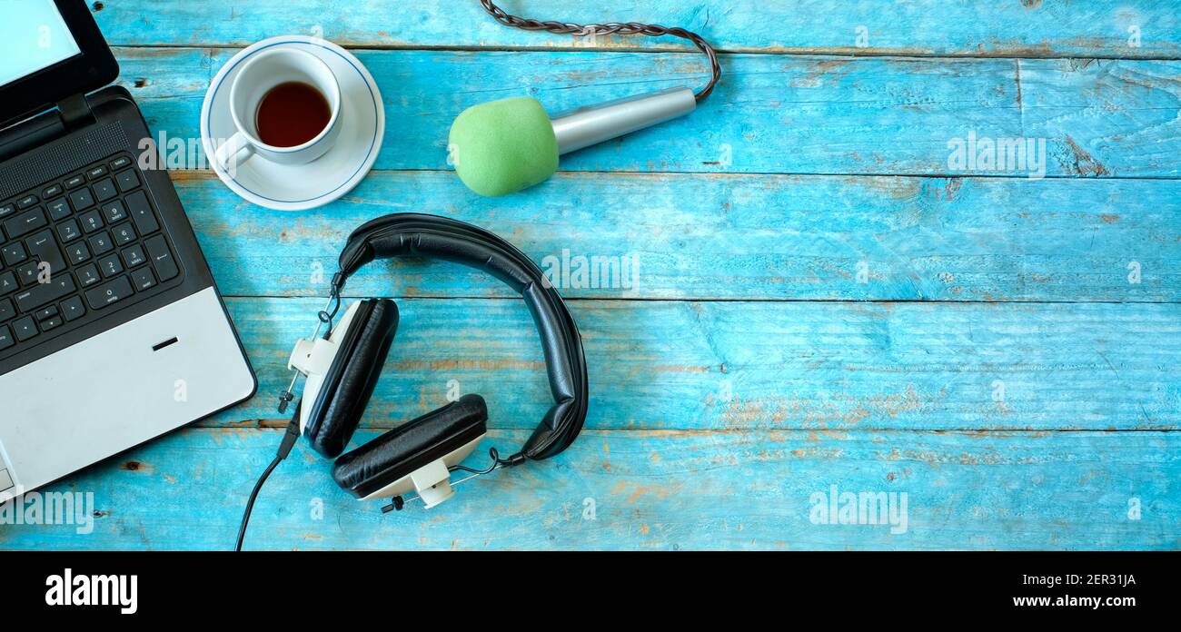 Musik-, Podcast- oder Hörbuch-Konzept, Flat-Lay mit Kopfhörer, Mikrofon, Kaffee und Laptop auf blauem Holztisch Stockfoto