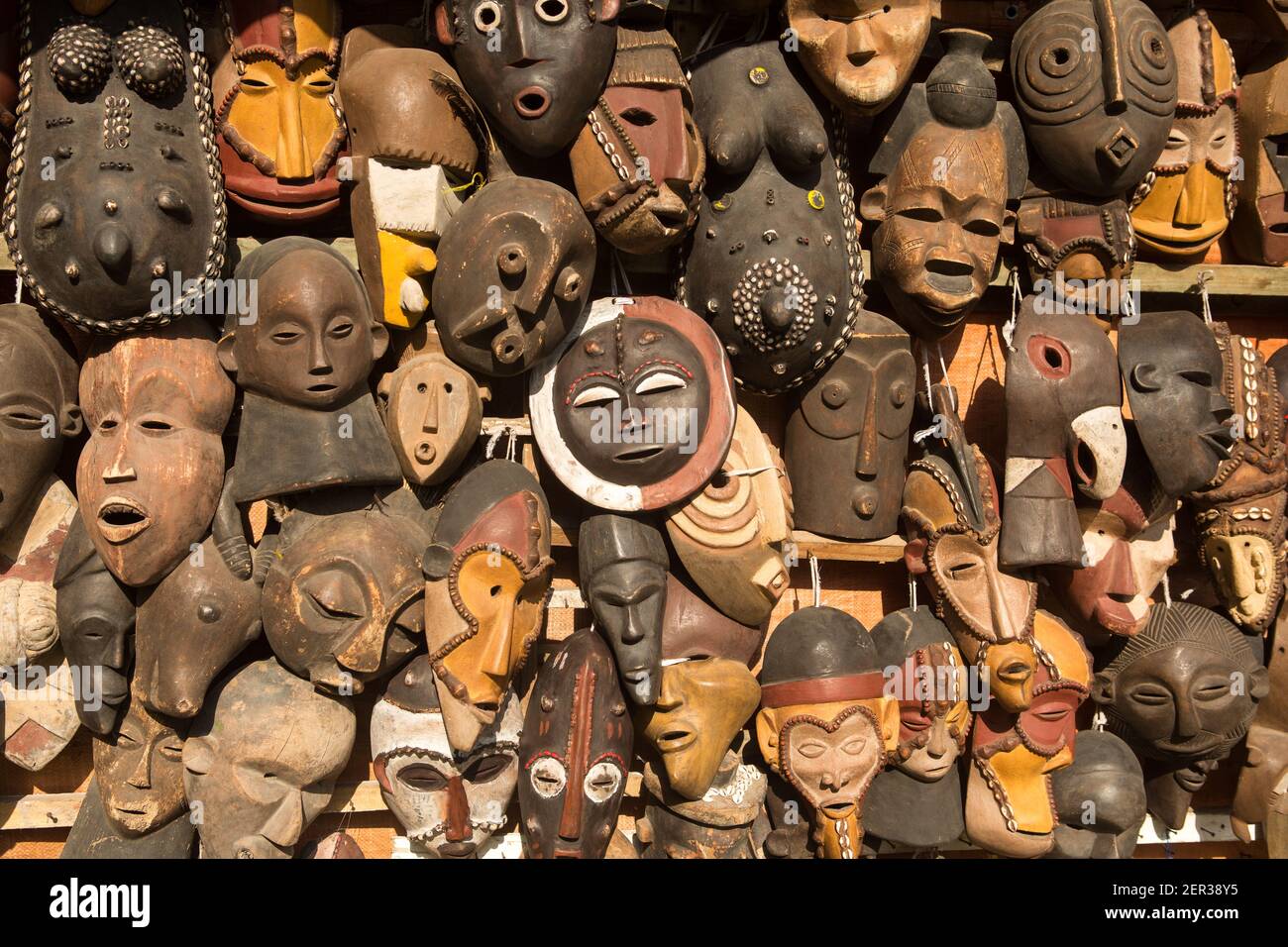 Traditionelle afrikanische Masken hängen zum Verkauf in einem Marktstand. Stockfoto