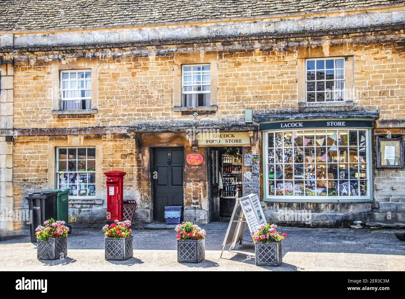 7-25-2019 Lacock UK - Dorfladen und Post geöffnet An sonnigen Tag in Lacock UK mit Blumen vor Von alten Gebäuden mit Postkarten auf Rack Stockfoto