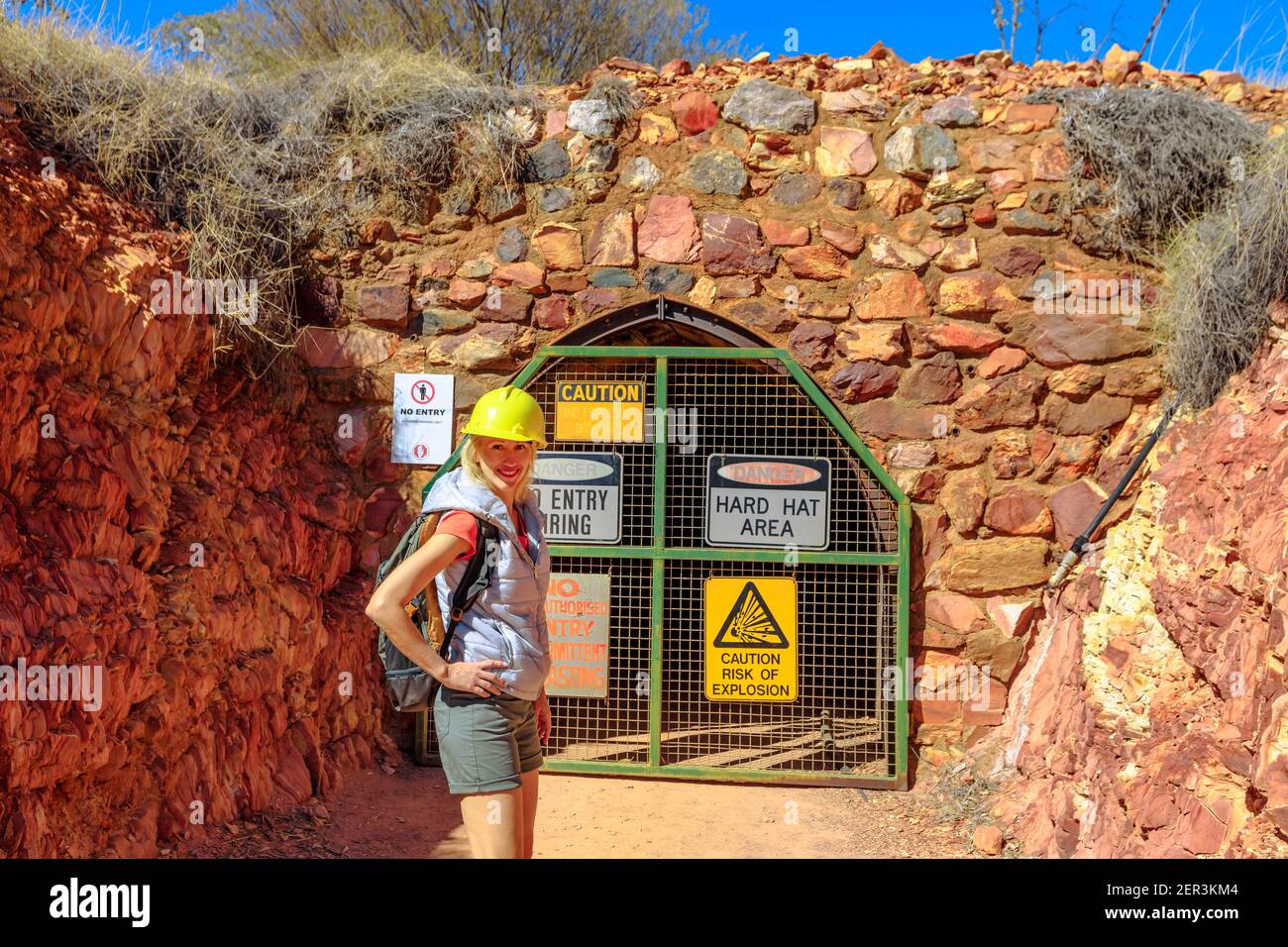 Glückliche Frau Tourist mit Bergmann Helm am Eingang der Tunnelhöhle des Battery Hill Mining Center. Tourismus in Tennant Creek im Northern Territory Stockfoto
