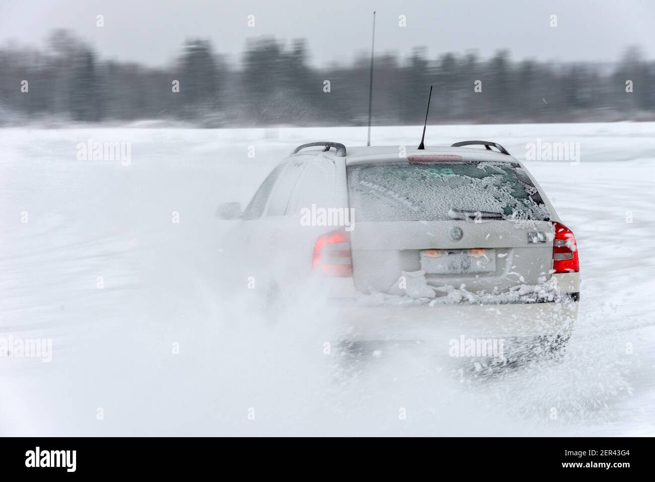 Ein Polizeifahrzeug dreht sich in eine breite Kurve auf einer Rutschwanne und sendet Schneesprühen in seinem Gefolge auf einer Polizeifahrer-Schulstrecke in der Nähe von Pieksamaki i Stockfoto