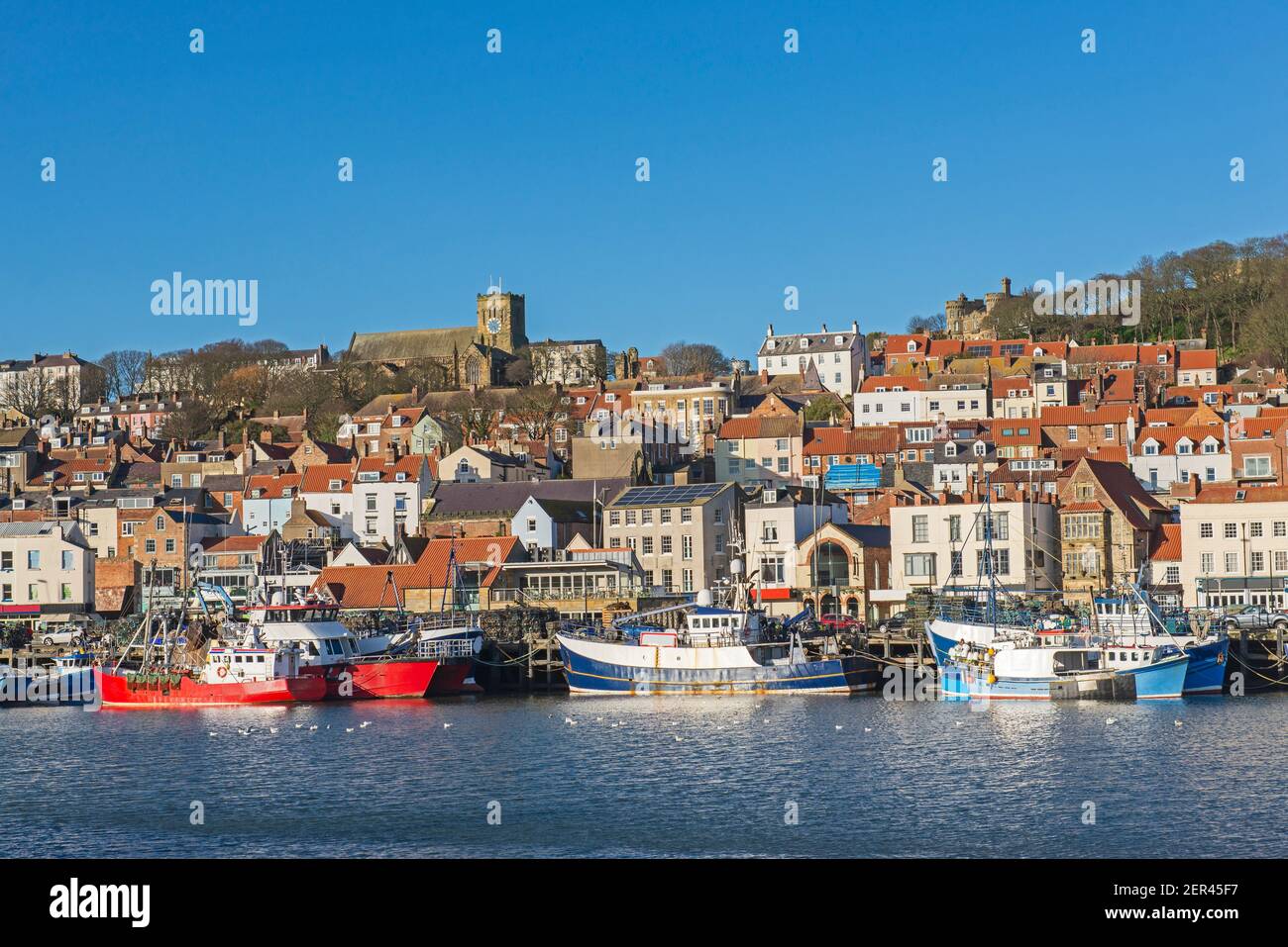 Landschaft Panoramablick auf die Küstenstadt Hafenfront mit Mittelalterliche Kirche auf einem Hügel und Fischerboote Stockfoto