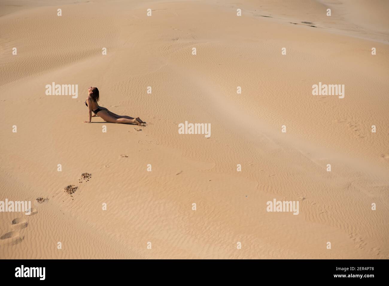 Junge Frau tut erstreckt sich am Strand Stockfoto