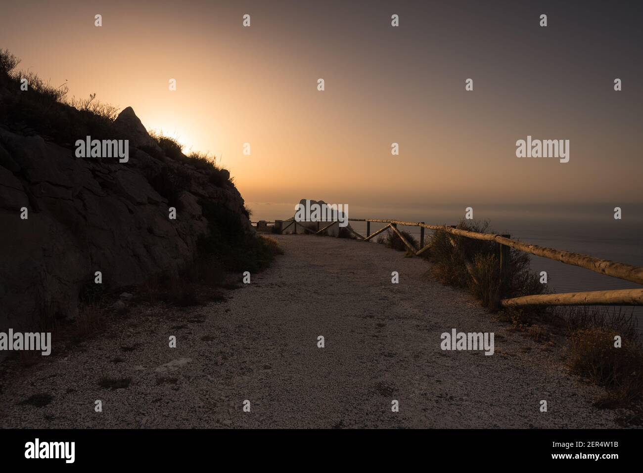 Die Sonnenaufgangssonne erscheint um die Kurve am Ende der unbefestigten Straße, Spanien Stockfoto