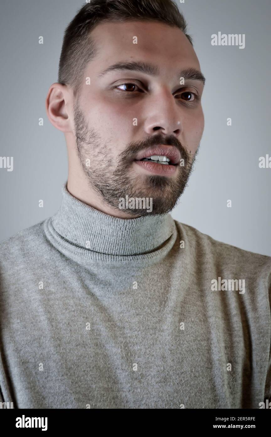 Porträt eines jungen braunhaarigen Mannes mit kurzem Bart Und einen grauen Rollkragenpullover Stockfoto
