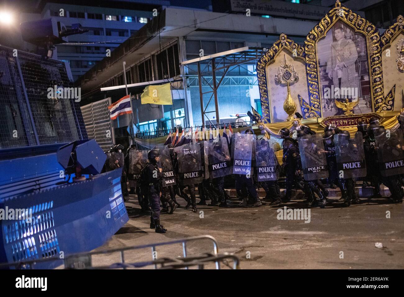 Neben einem Porträt des thailändischen Königs Maha Vajiralongkorn während einer Anti-Regierungsdemonstration in Bangkok stehen die Bereitschaftspolizisten hinter ihren Schilden.Tausende von prodemokratischen Demonstranten versammelten sich in der Vibhavadi Rangsit Road vor dem Infanterie-Regiment 1st in der Nähe des Premierministers und forderten den Rücktritt des thailändischen Premierministers und Die Reform der Monarchie in Bangkok, Thailand. Die Demonstranten verurteilten auch die Anwendung des ‘Lese majeste Gesetz' unter dem Abschnitt 112 des Strafgesetzbuches. Der von ‘FreeYouth' organisierte Protest endete mit mehreren Zusammenstößen, dem Einsatz von Wasserwerfern, Tränengas Stockfoto