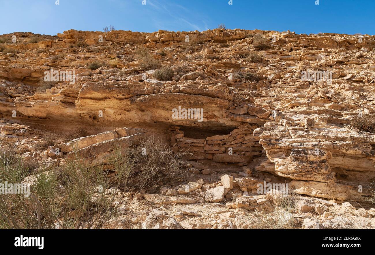 Ein zwei Meter moderner beduinenvorrat ist fast unsichtbar Unter einem Kalksteinüberhang über einem wadi in der Nähe des Randes Des makhesh ramon Kraters Stockfoto