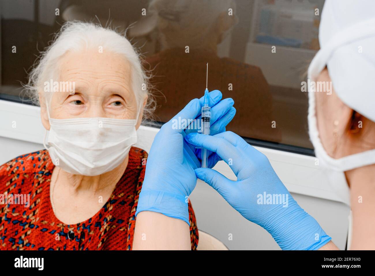 Ältere Frau erhält Coronavirus-Impfstoff. Der Arzt impft eine ältere Frau, die eine chirurgische Maske trägt Stockfoto
