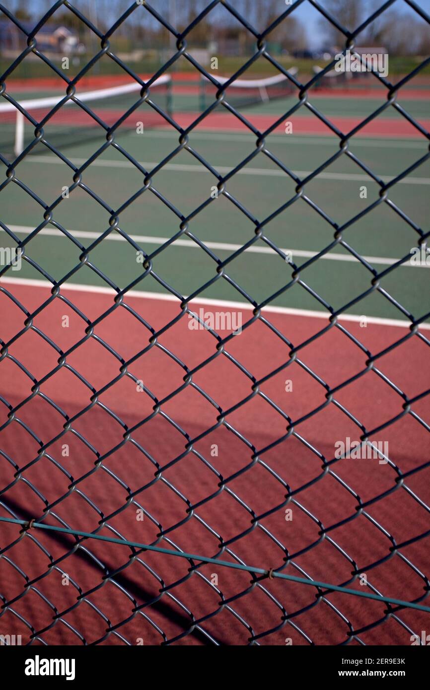 Blick durch Kettengliederzaun auf leere Tennisplätze. England Stockfoto