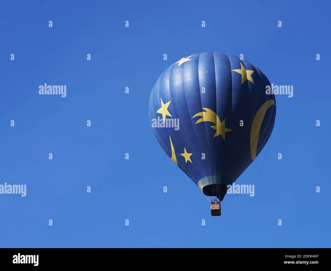 Nahaufnahme des blauen und gelben Heißluftballons vor dem Hintergrund des blauen Himmels und der Hügel. Von der Seite betrachtet. Stockfoto