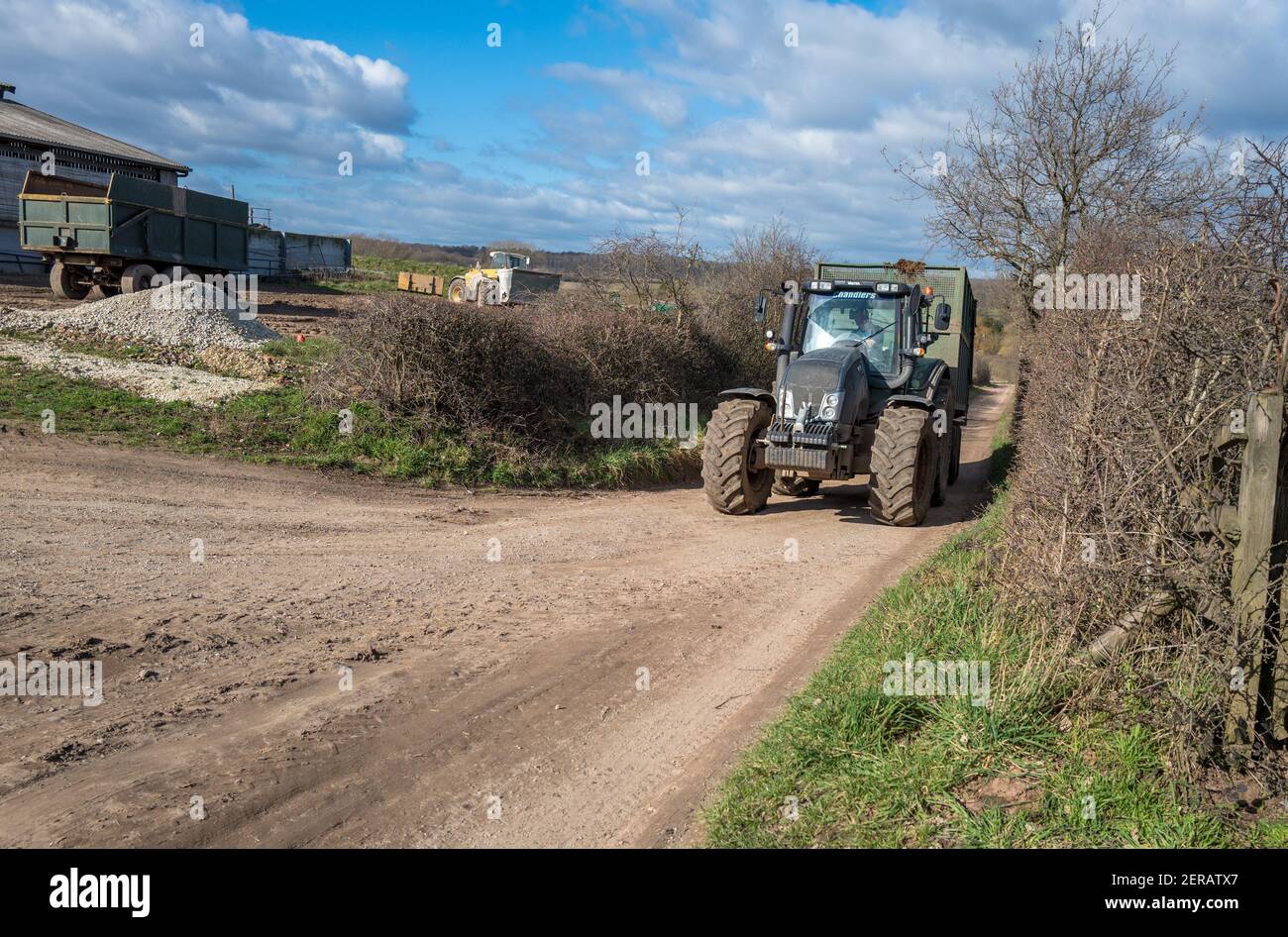 Valtra T173 Traktor zieht einen großen Anhänger auf einer staubigen Spur. Stockfoto