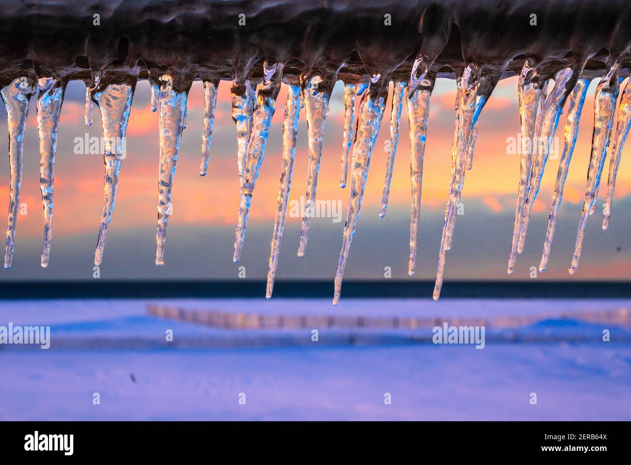 Eiszapfen an einem Wintertag mit buntem Sonnenuntergang Im Hintergrund Stockfoto