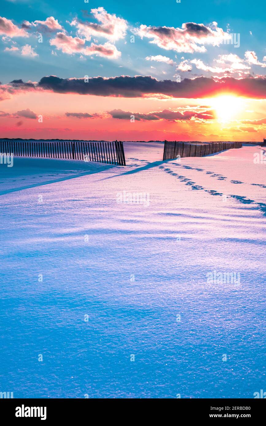 Winterszene unter farbigem Himmel bei Sonnenuntergang am schneebedeckten Strand. Jones Beach State Park, Long Island NY Stockfoto