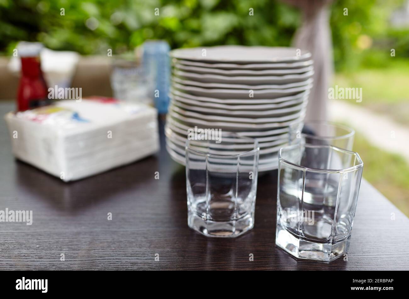 Verschwommenes Bild von leeren Gläsern auf dem Tisch im Restaurant im Freien. Feiertage, Geburtstagsfeier und Dekorationskonzept Stockfoto