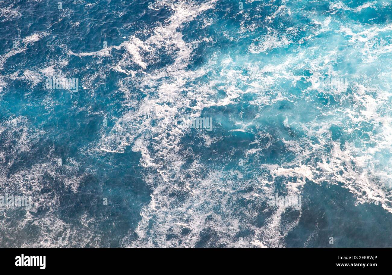 Weißer Schaum bedeckt die Oberfläche des Karibischen Meeres in der Nähe der felsigen Küsten der Insel Redonda, Antigua und Barbuda, Karibik. Stockfoto