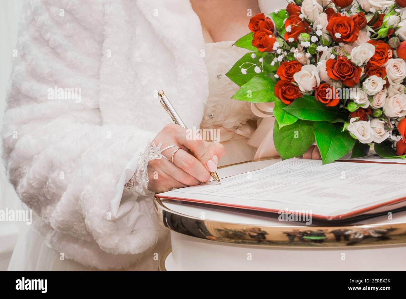 Die Hand der Braut setzt den Signaturstift auf die Einwilligungsheirat bei der Nahaufnahme der Hochzeit. Stockfoto