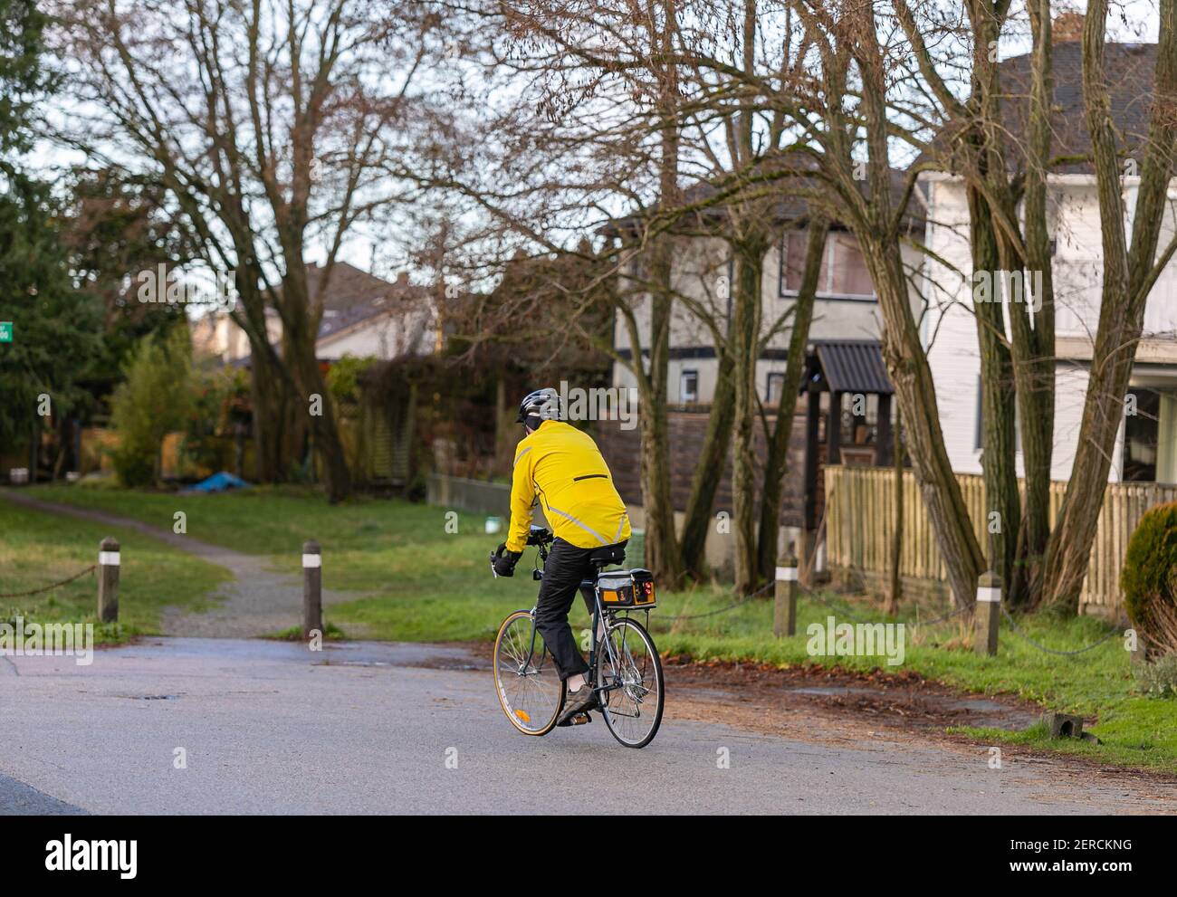 Ein Mann in einer gelben Jacke und Helm auf dem Land auf einem Fahrrad fahren. Straßenansicht, Reisefoto, selektiver Fokus, Konzeptfoto Sportaktivität. Stockfoto