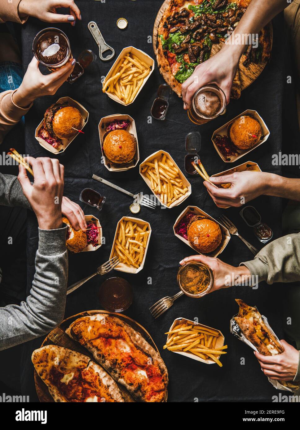 Lockdown Familie Fast Food Abendessen von Lieferservice. Flat-Lay von Freunden, die Quarantäne Home Party mit Burger, Pommes, Sandwiches, Pizza, Bier o Stockfoto