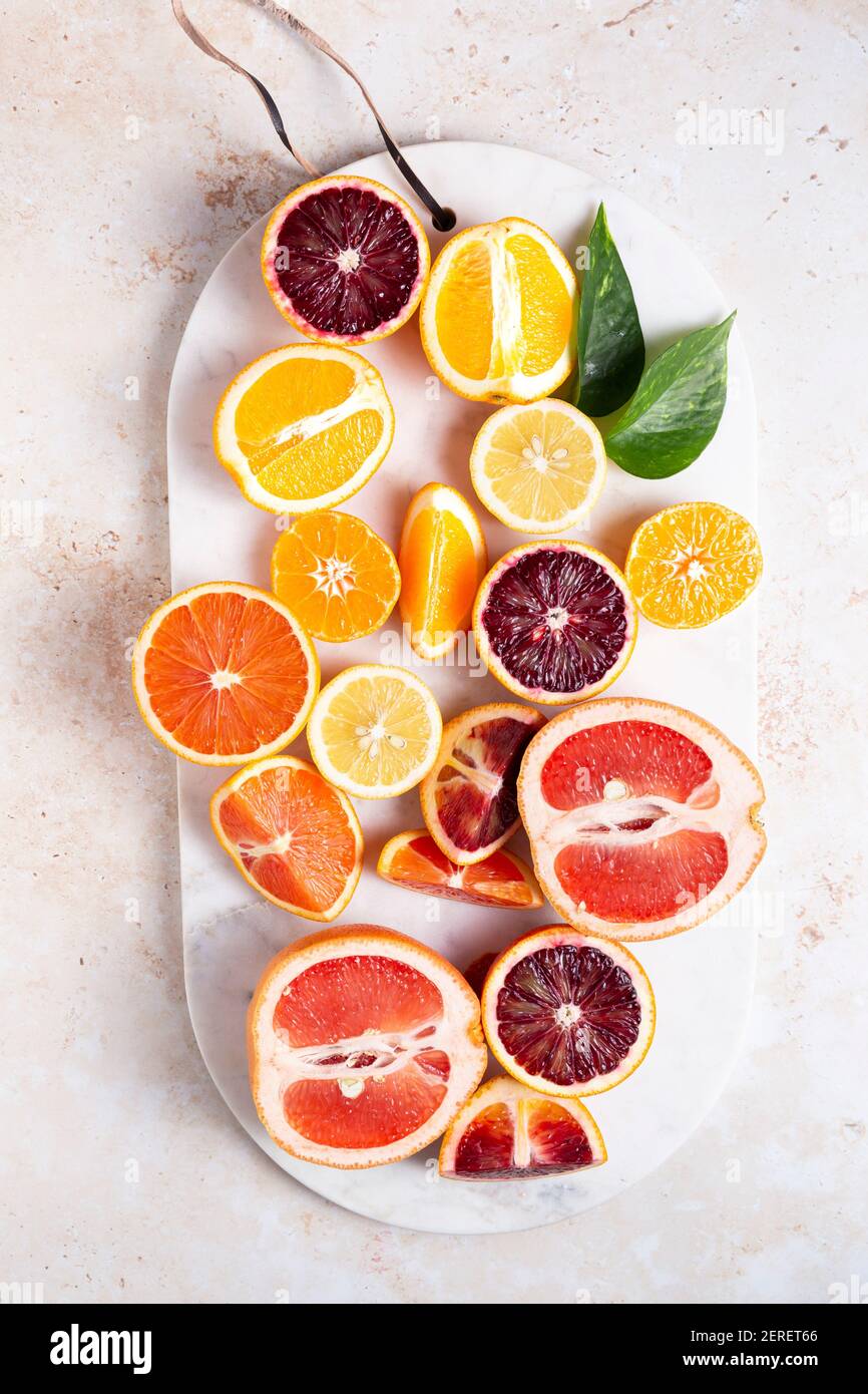Flach legen Zitrusfrüchte mit geschnittenen Zitronen, Grapefruits, Orangen, Blutorangen und Zitronen auf einem Schneidebrett. Stockfoto