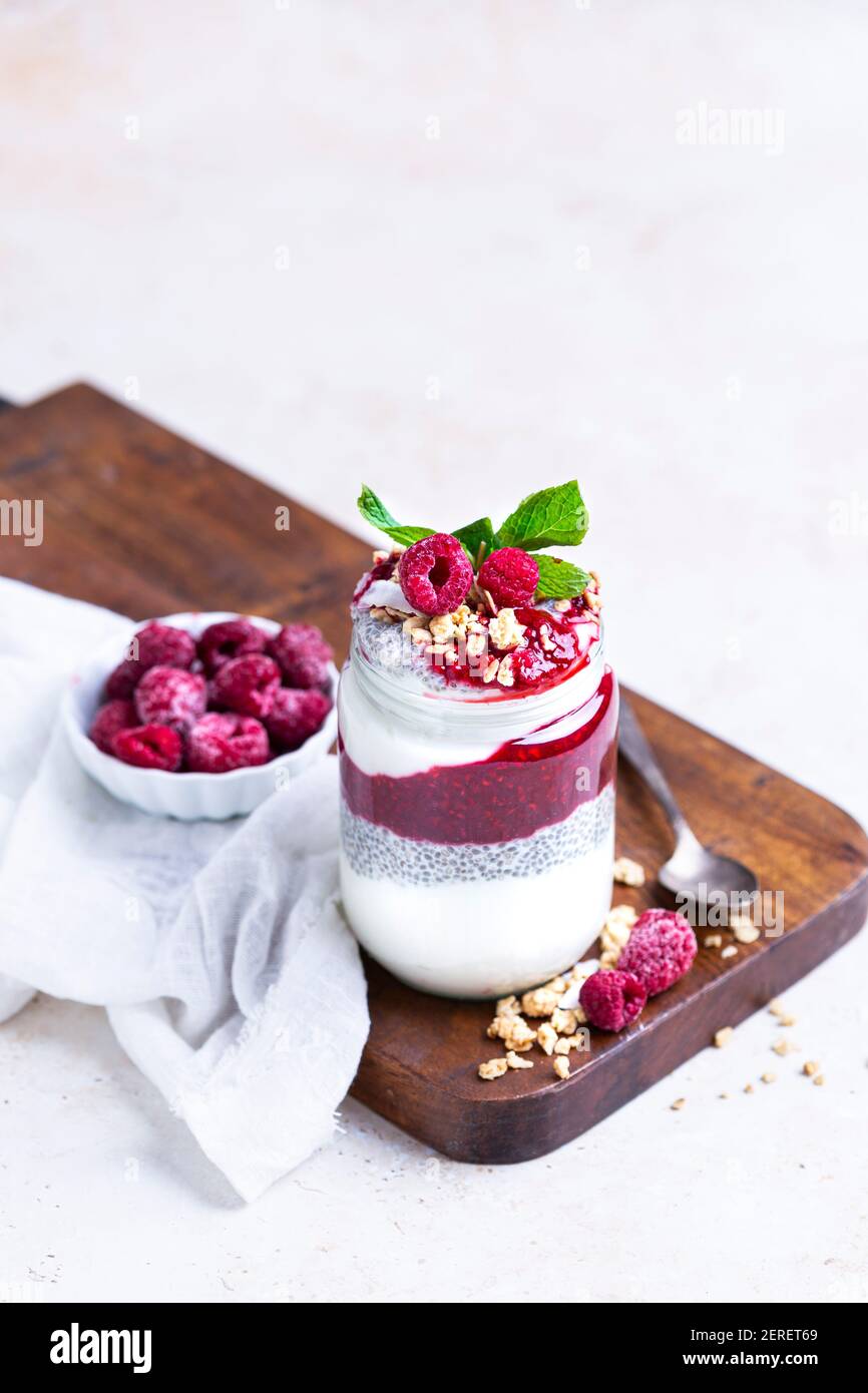 Himbeermarmelade, Chia Pudding und Joghurt. Garniert mit Granola, um einen Parfait in einem Glas zu machen. Stockfoto