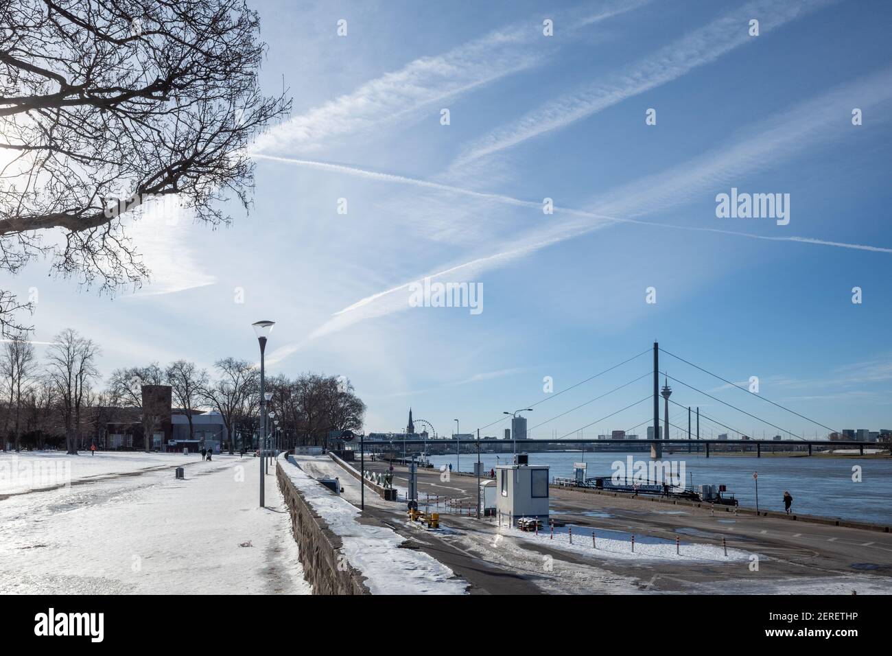 Sonniger Blick im Freien auf den Rheinpark Golzheim, großer, von Schnee bedeckter Park am Rheinufer und Promenade neben der Seebrücke. Stockfoto