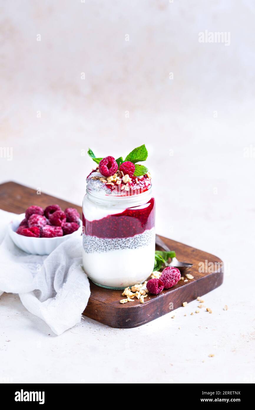 Himbeermarmelade, Chia Pudding und Joghurt. Garniert mit Granola, um einen Parfait in einem Glas zu machen. Stockfoto