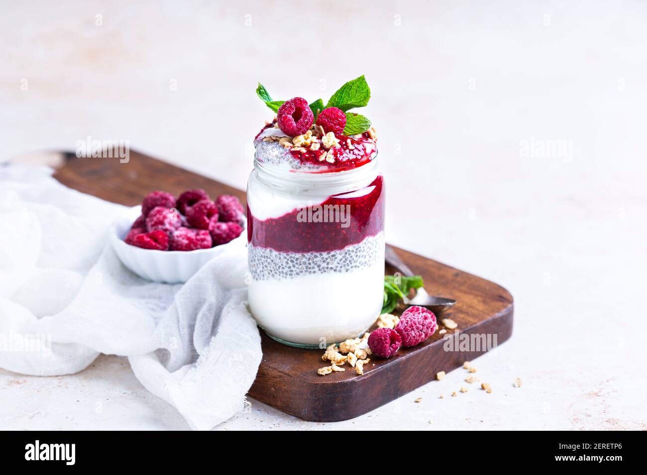 Himbeermarmelade, Chia Pudding und Joghurt. Garniert mit Granola, um einen Parfait in einem Glas zu machen. Stockfoto