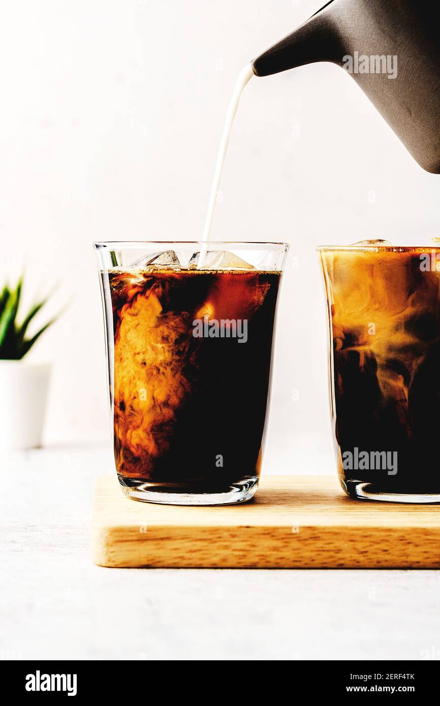 Eiskaffee und Milch werden auf einem Schneidebrett serviert. Stockfoto