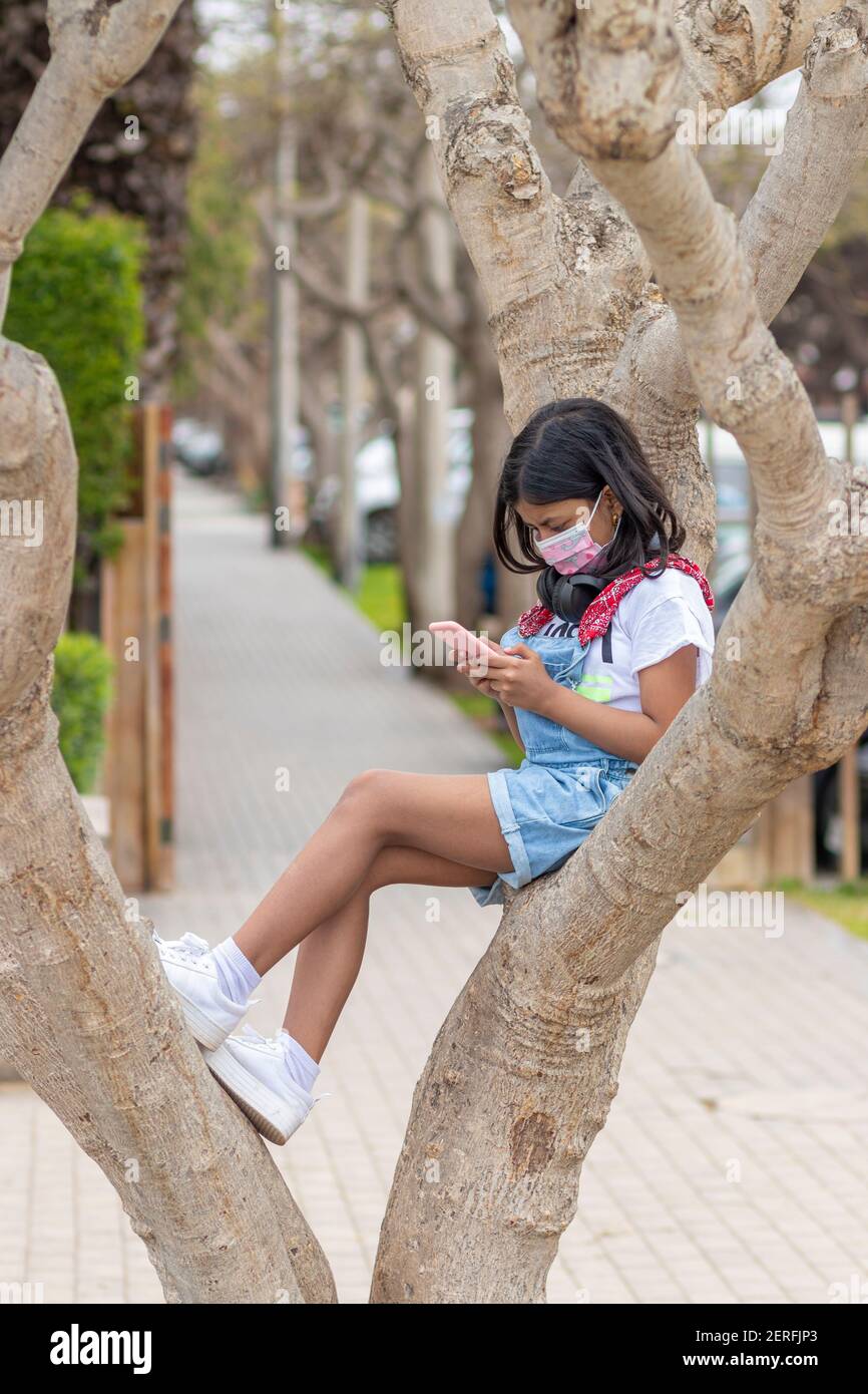 Das kleine Mädchen hört Musik mit ihren Kopfhörern an Ein Baum Stockfoto