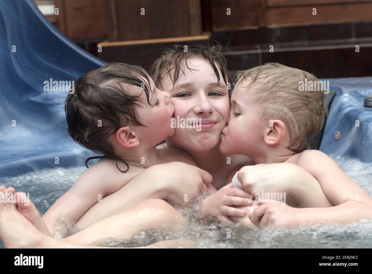 Kinder umarmen und lachen im Whirlpool Stockfoto