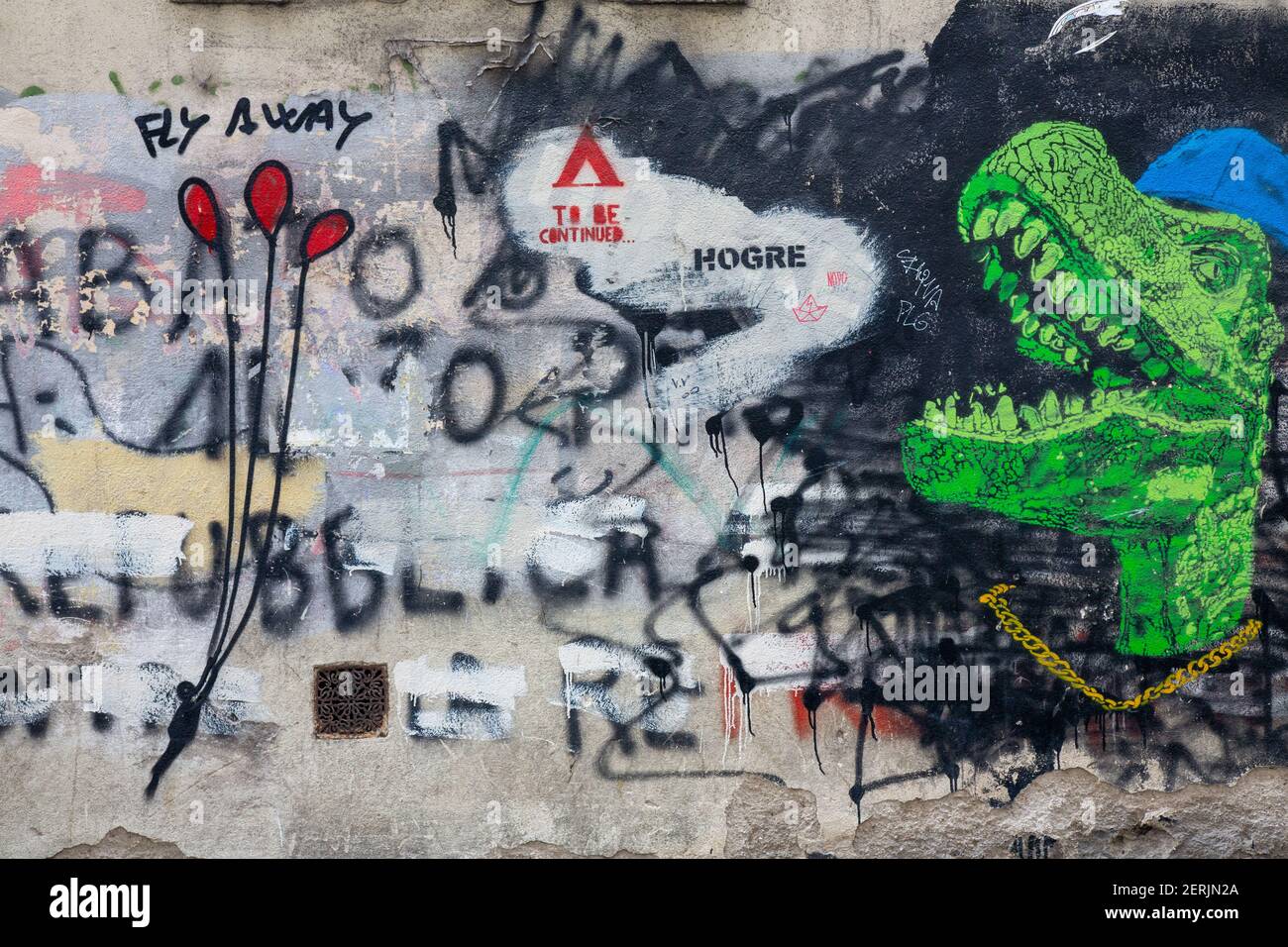 Eine strukturierte Betonwand mit Street Art einschließlich T rex Kopf Waring eine Kappe und ein Mann schwimmt auf Ballons bedeckt. Stockfoto