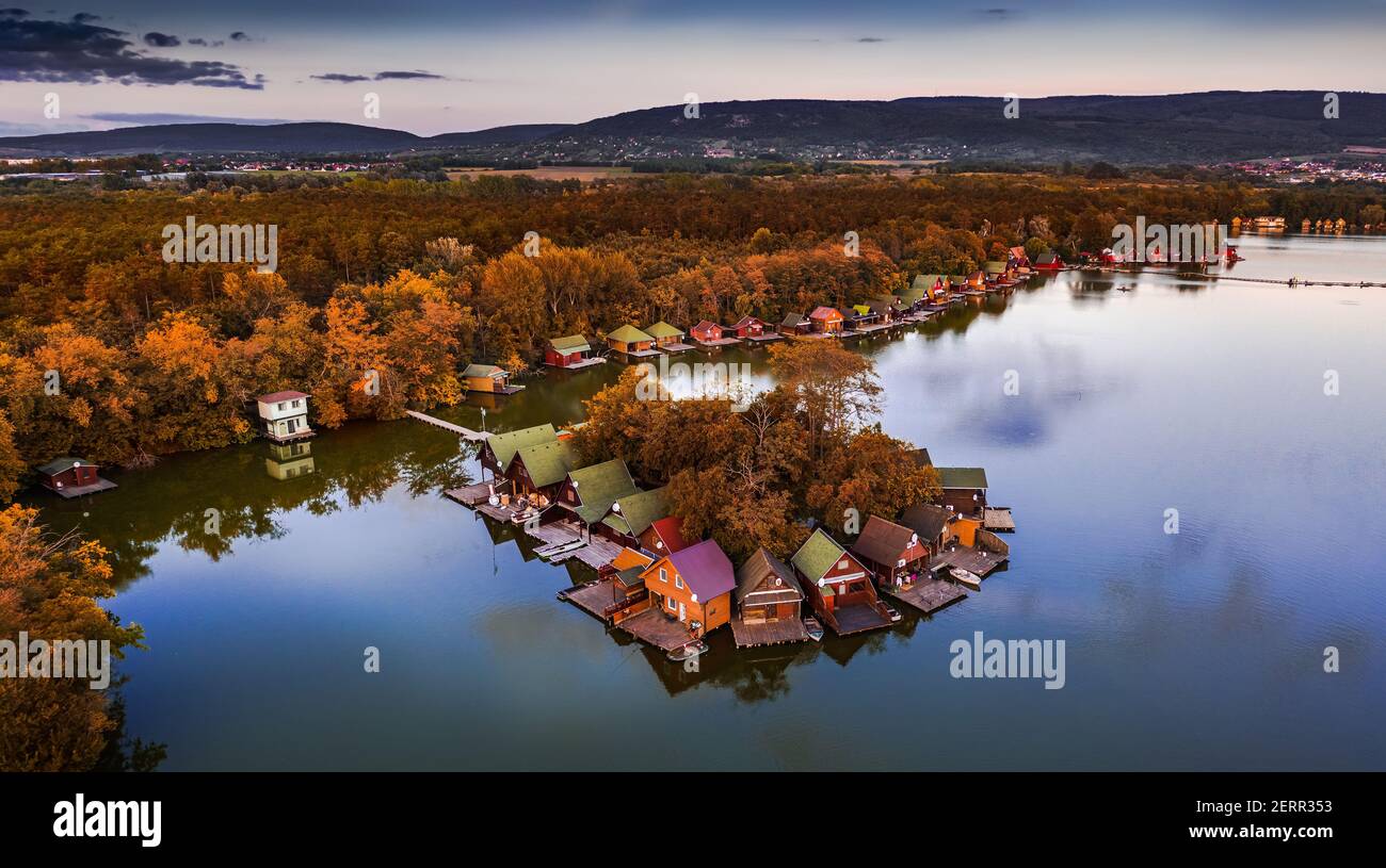 Tata, Ungarn - schöner Herbstuntergang über hölzernen Fischerhütten auf einer kleinen Insel am Derito-See (Derito-to) im Oktober mit klarem blauen Himmel und einem Stockfoto