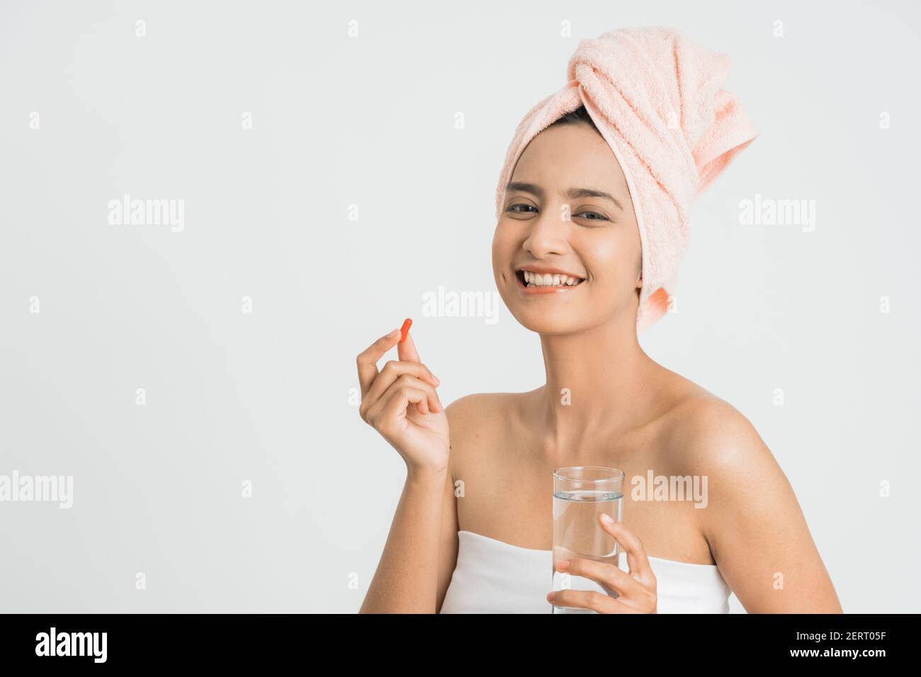 Junge asiatische Schönheit junge Frau essen Pillen und Trinkwasser auf weißem Hintergrund. Stockfoto