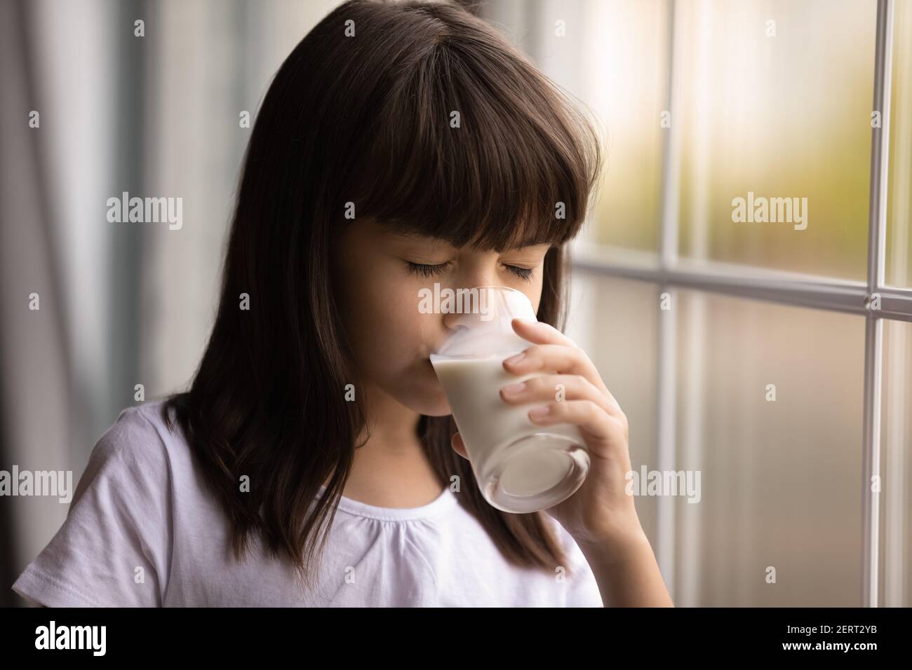 Kleine hispanische Mädchen trinken Milch aus Glas Stockfoto