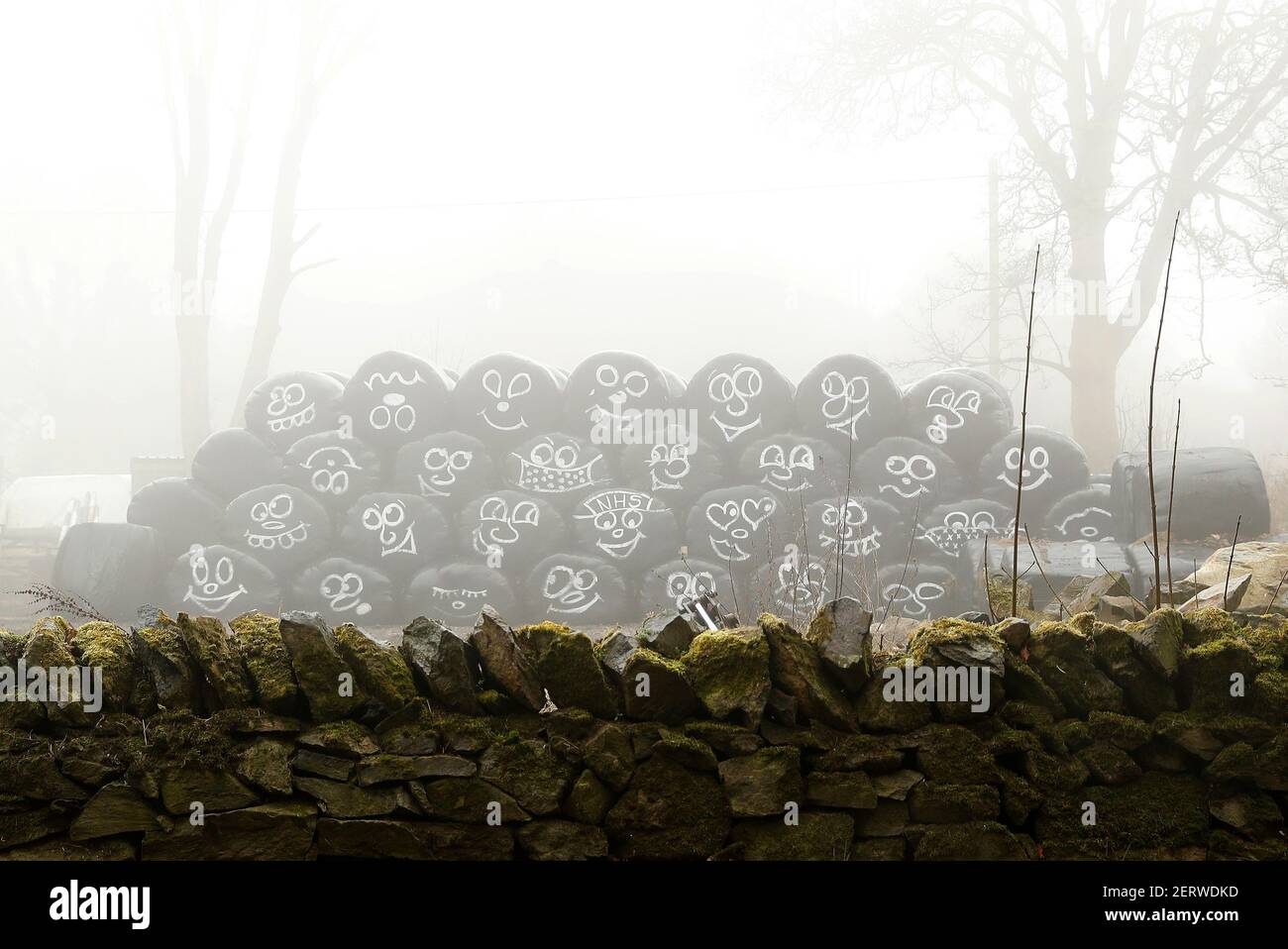 Coalville, Leicestershire, Großbritannien. 1st. März 2021. Wetter in Großbritannien. Ein mit Gesichtern bemalter Silagestapel steht im Nebel am ersten Tag der Meteorologischen Quelle. Credit Darren Staples/Alamy Live News. Stockfoto