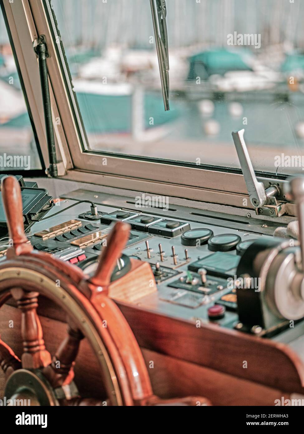 Nahaufnahme des Innenraums eines großen Motorbootes. Das Lenkrad und die Motorsteuerungen sind zu sehen und der Bootshafen schlurrte durch das Glasboot w Stockfoto