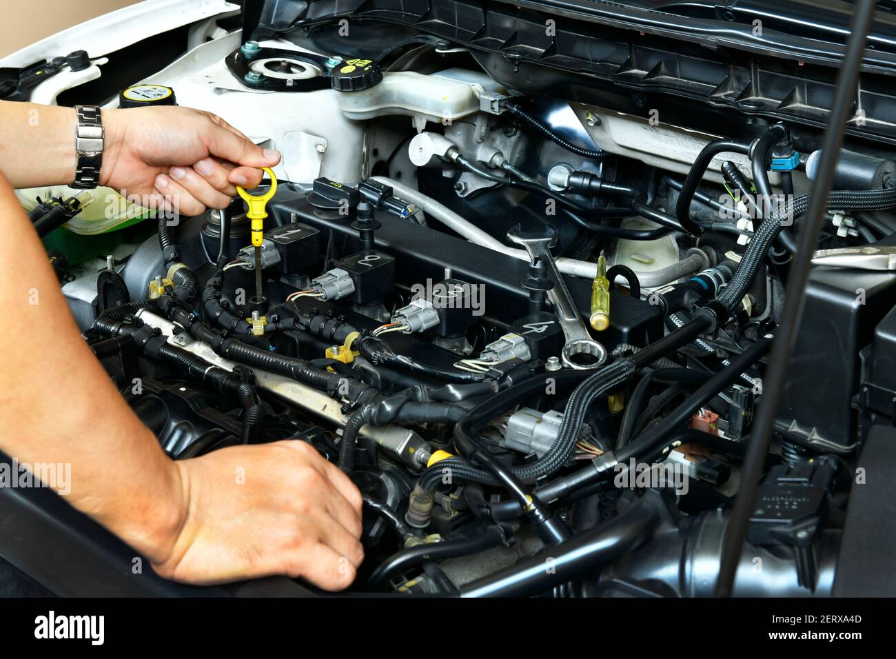 Ein professioneller Mechaniker hält den Ölmessstab und überprüft den Ölstand im Automotor Stockfoto