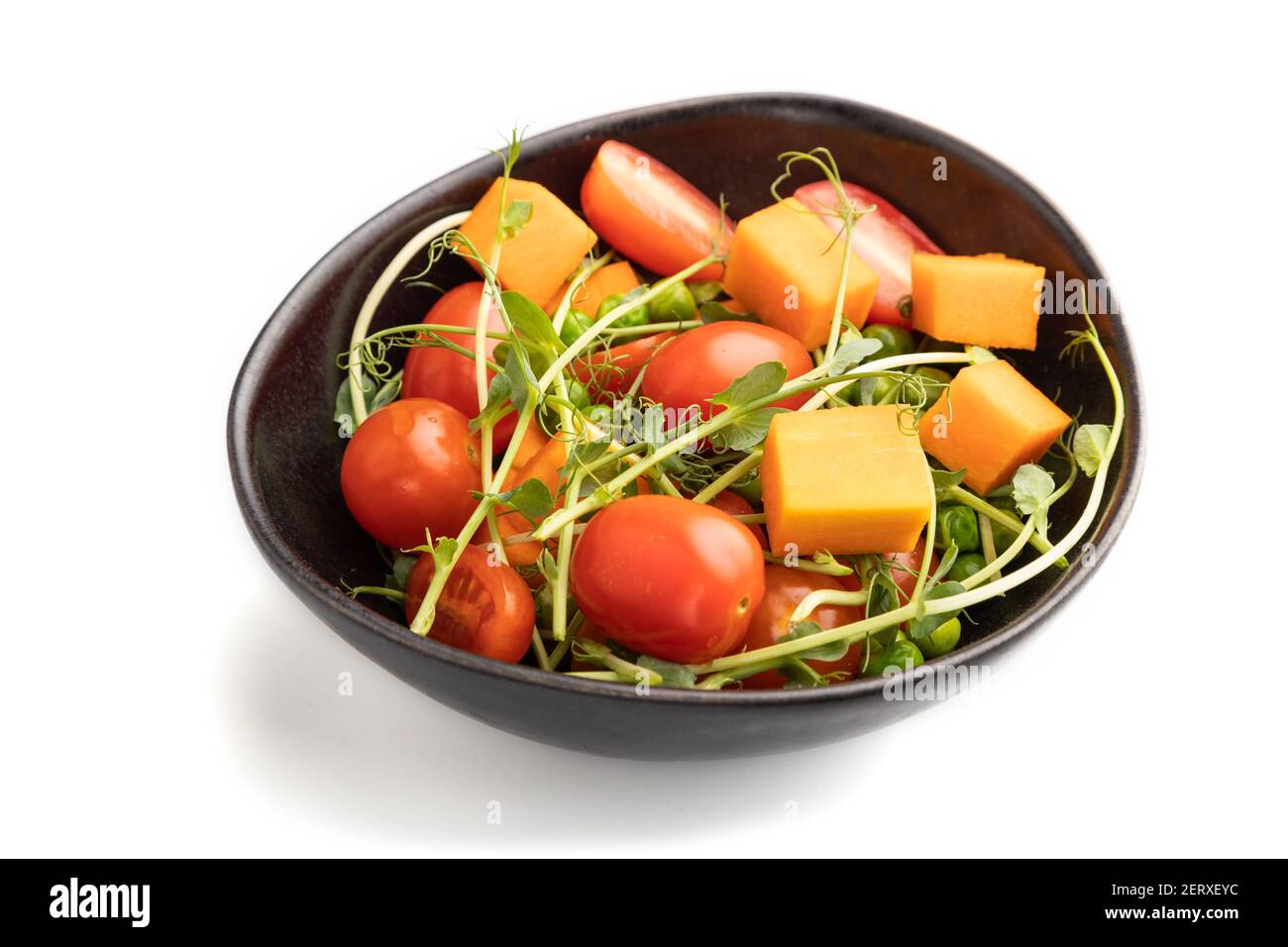 Vegetarischer Gemüsesalat aus Tomaten, Kürbis, mikrogrüne Erbsensprossen isoliert auf weißem Hintergrund. Seitenansicht, Nahaufnahme. Stockfoto