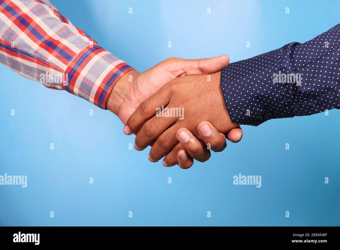 Zwei Personen Handschlag vor blauem Hintergrund, Stockfoto