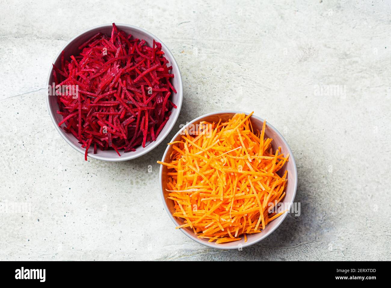 Gehackte Rüben und Karotten in grauen Schüsseln. Zutaten für gesundes Kochen. Stockfoto