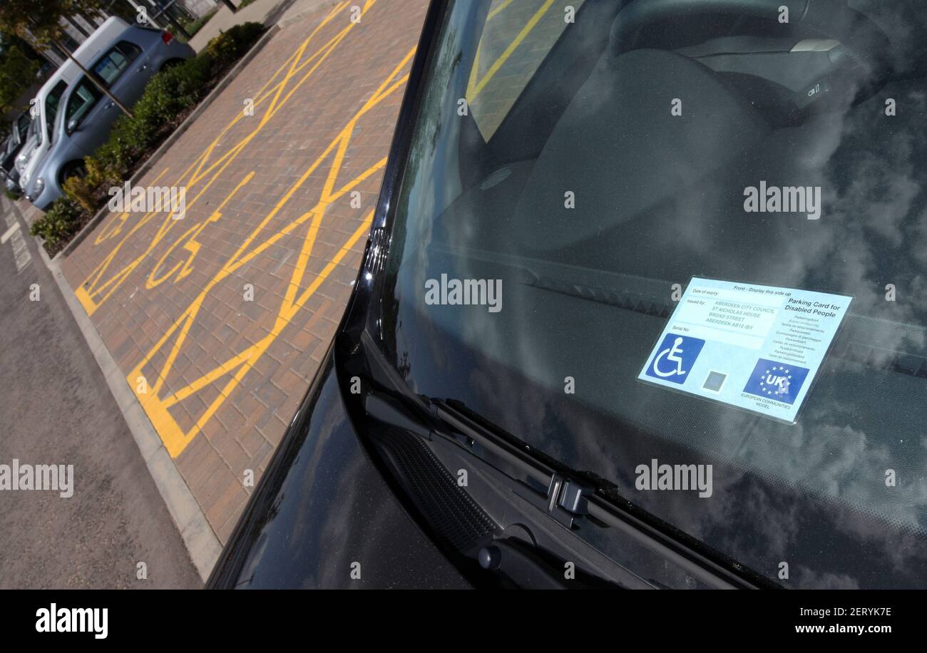 Eine Windschutzscheibe mit einem Behindertenausweis und Markierungen für Inhaber von Behindertenausweisen nur auf einem Parkplatz in Schottland, Großbritannien Stockfoto