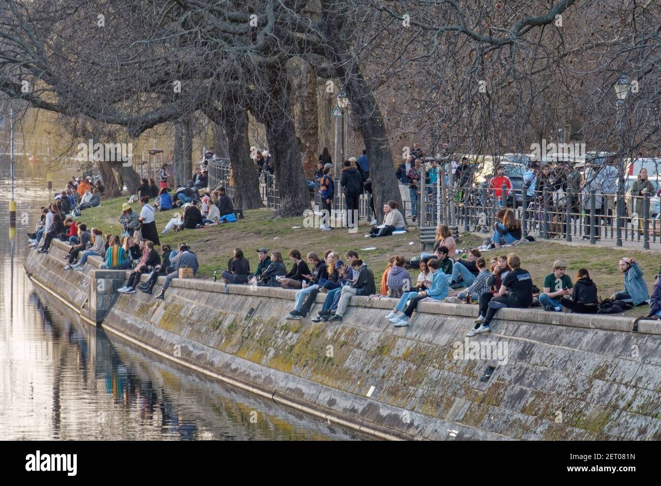Junge Leute sitzen am Landwehrkanal in Kreuzberg, Urbanhafen, Berlin, Vorfruehling, Lockdown, Aha-Regeln, Stockfoto